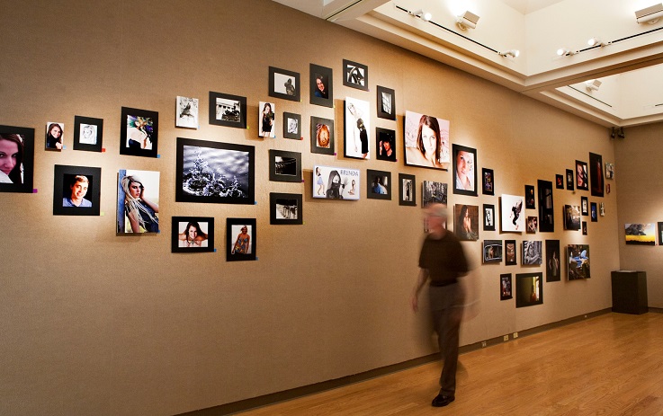 Wall of student photos from a recent William Woods University Senior Art Show exhibit